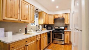 A modern kitchen with wooden cabinets, stainless steel appliances, and a white countertop. - Cozy Mt. Baker Escape • Fireplace • Pets (Glacier)