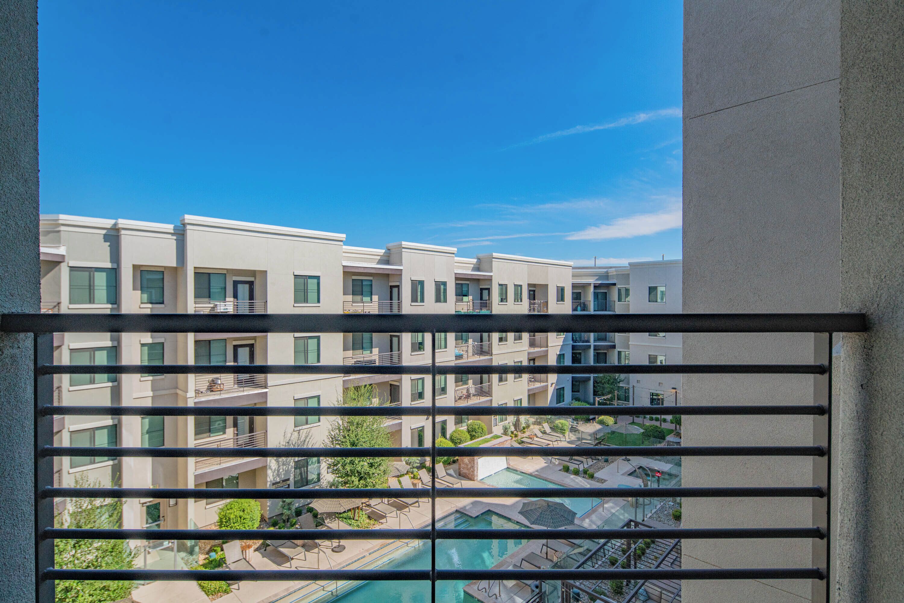 A view of a modern apartment building with multiple balconies and a swimming pool area.