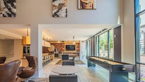 A modern hotel lobby with a pool table, comfortable seating, a kitchen area, and large windows offering views. - ROVE LIVING/KL - Alta North Central (Phoenix)