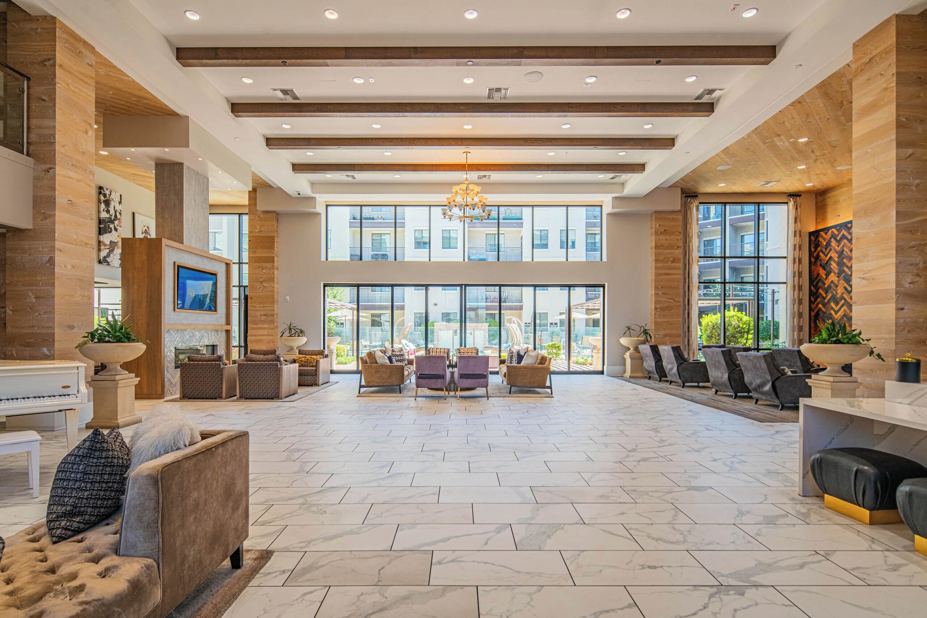 A spacious lobby with a piano, seating area, and large windows offering views of the outside.