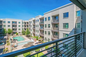 Ein modernes Apartmenthaus mit Pool auf dem Dach, Sitzgelegenheiten im Freien und wolkenlosem, blauem Himmel.