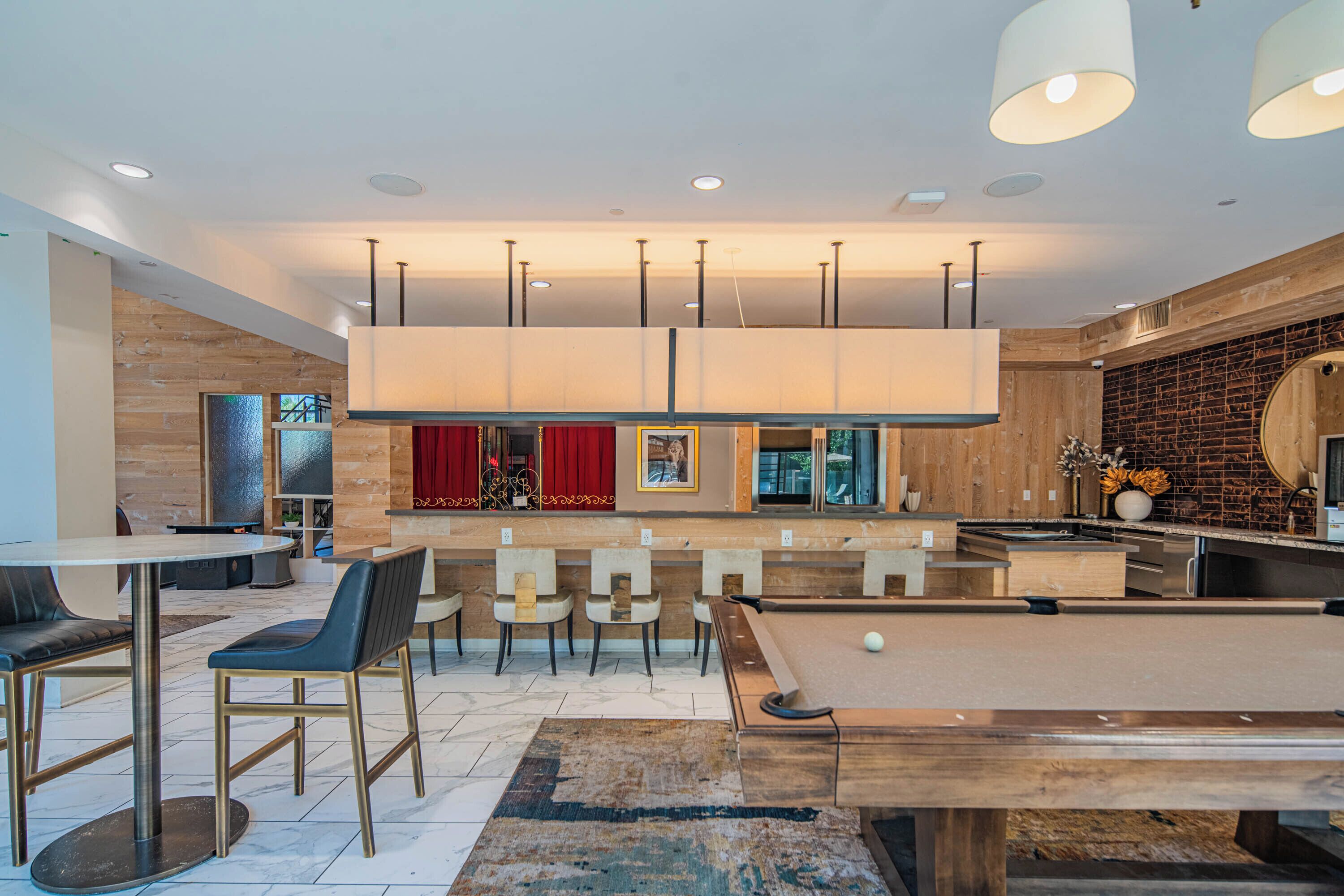 A modern indoor pool area with a pool table, seating, and a bar.