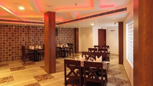 A dining area with wooden tables and chairs, patterned floor tiles, and a wall with a geometric design. - HOTEL DIAMOND FORT (Karunagappally)