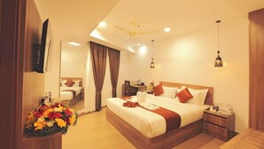 A hotel room with a large bed, a desk, a chair, a mirror, and a flower arrangement. - HOTEL DIAMOND FORT (Karunagappally)
