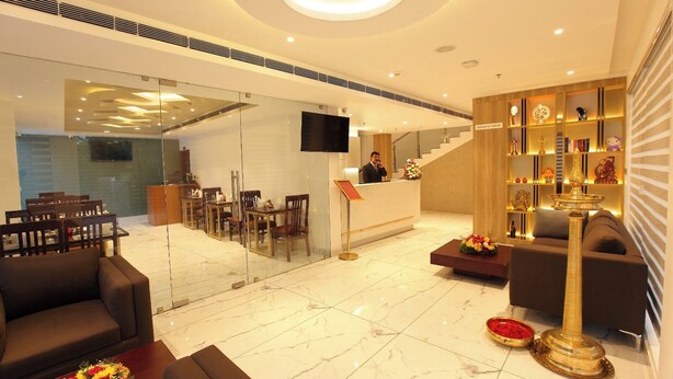 A modern hotel lobby with a reception desk, seating area, and a staircase. - HOTEL DIAMOND FORT (Karunagappally)