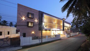 A modern building with a large glass facade, a gated entrance, and a well-lit exterior. - HOTEL DIAMOND FORT (Karunagappally)