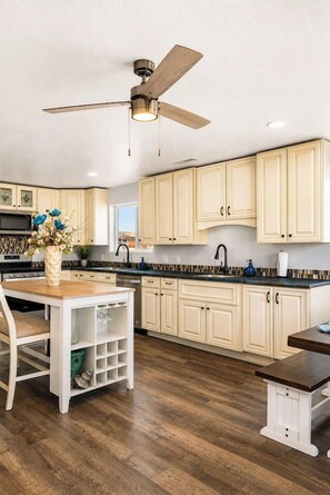 A kitchen with wooden cabinets, a ceiling fan, and a dining area with a table and chairs.