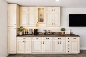 Una cocina con armarios blancos, una encimera oscura y varios electrodomésticos.