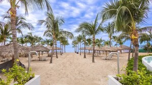 A beach with palm trees, thatched umbrellas, and a pool. - Marítima Beach Condo, 2BR, Deluxe, 2 Pools, BBQ, Balconies & Great Amenities (Flamingos)