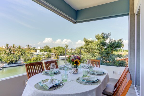 Mesa para cuatro personas con vista al agua y vegetación.