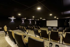 Un teatro con hileras de asientos, una pantalla grande y luces en el techo.