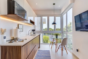 A modern kitchen with a large island, built-in appliances, and a dining area with a glass table and chairs. - Casa Azul New Deluxe Studio Apt w/Great Views, Pool & Jacuzzi (Nuevo Nayarit)