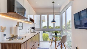A modern kitchen with a large island, built-in appliances, and a dining area with a glass table and chairs.