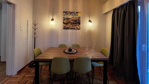 Ein Essbereich mit Holztisch, vier Stühlen, einem Bild an der Wand und Pendelleuchten.