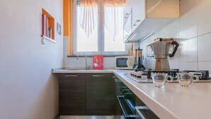 Une cuisine compacte équipée d’une fenêtre, d’un four à micro-ondes, d’une machine à café et d’un évier.
