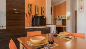 Une cuisine moderne avec une table à manger pour deux personnes, dotée d’un téléviseur à écran plat au-dessus du comptoir et agrémentée d’œuvres d’art décoratives sur les murs.