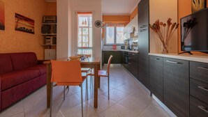 Un espace de vie compact comprenant un coin repas, une kitchenette et un canapé rouge.