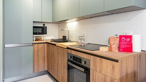 A modern kitchen with light wood cabinets, a black microwave, a built-in oven, and a coffee machine. - Casa Gianna by Wonderful Italy (Siracusa)