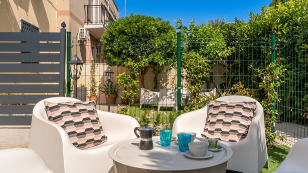 A patio with white chairs, a round table, and a coffee pot. - Casa Gianna by Wonderful Italy (Siracusa)