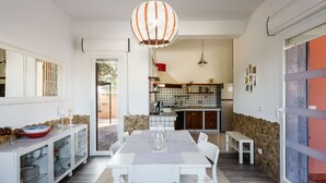 Una cocina moderna con comedor, que incluye una mesa blanca, sillas y una lámpara colgante.