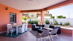 Un patio con una mesa de comedor y sillas, un sofá y una mesa auxiliar.