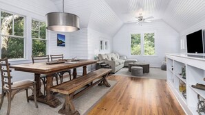 Une pièce spacieuse comprenant une table à manger en bois, des bancs, un canapé et un téléviseur.