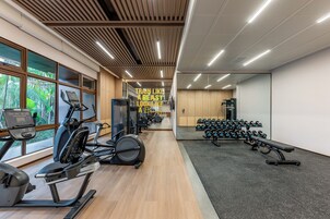 A gym with cardio machines, weightlifting equipment, and a mirror wall.