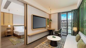 Habitación de hotel con cama, televisión, mesa, silla y vistas a la ciudad.