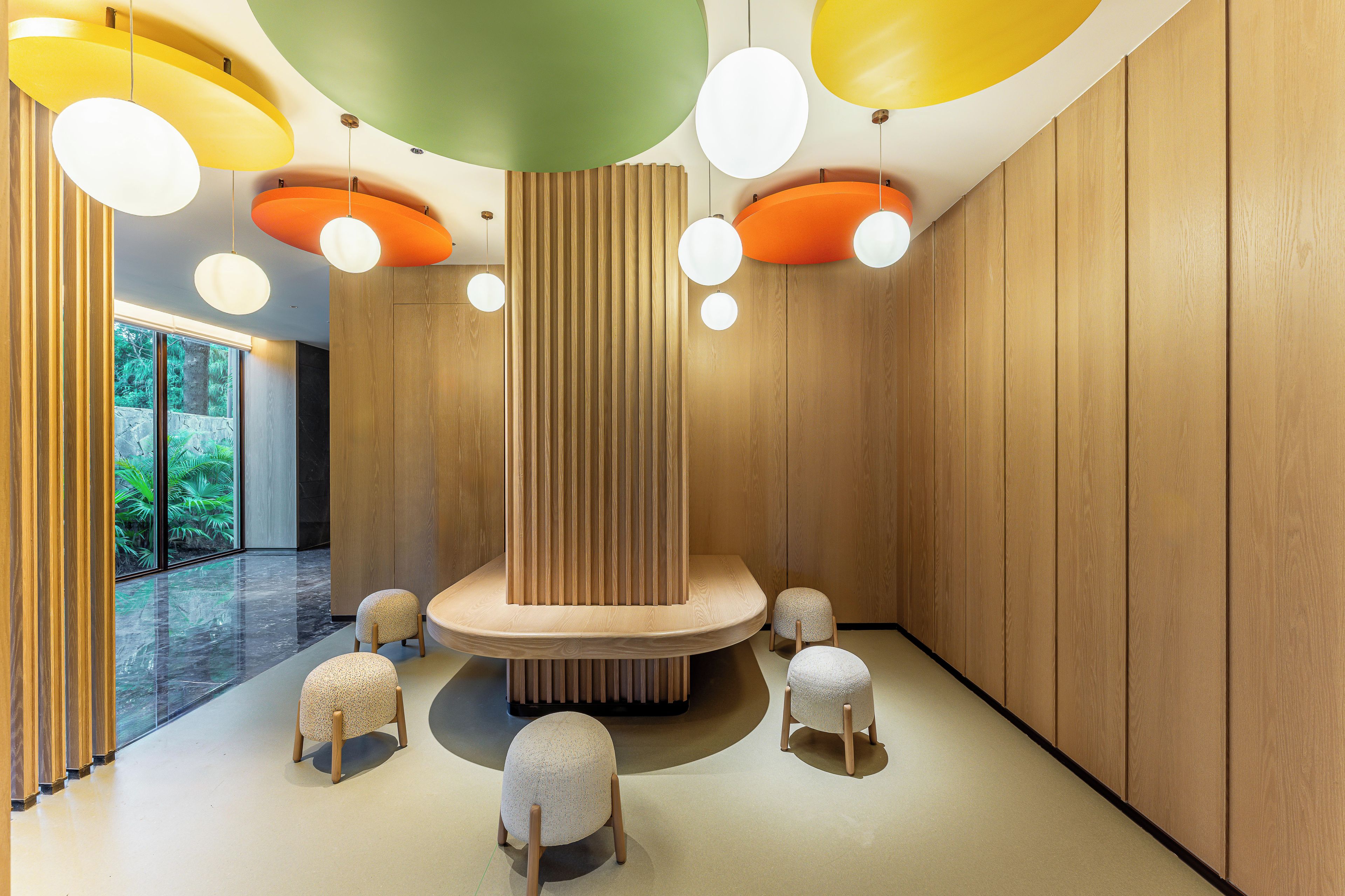 A modern interior with wooden panel walls, a central seating area, and pendant lighting.
