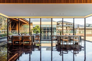 A modern interior with a reflective floor, large windows, and a view of the building's exterior. - Holiday Inn Puer Jingmai by IHG (Pu'er)