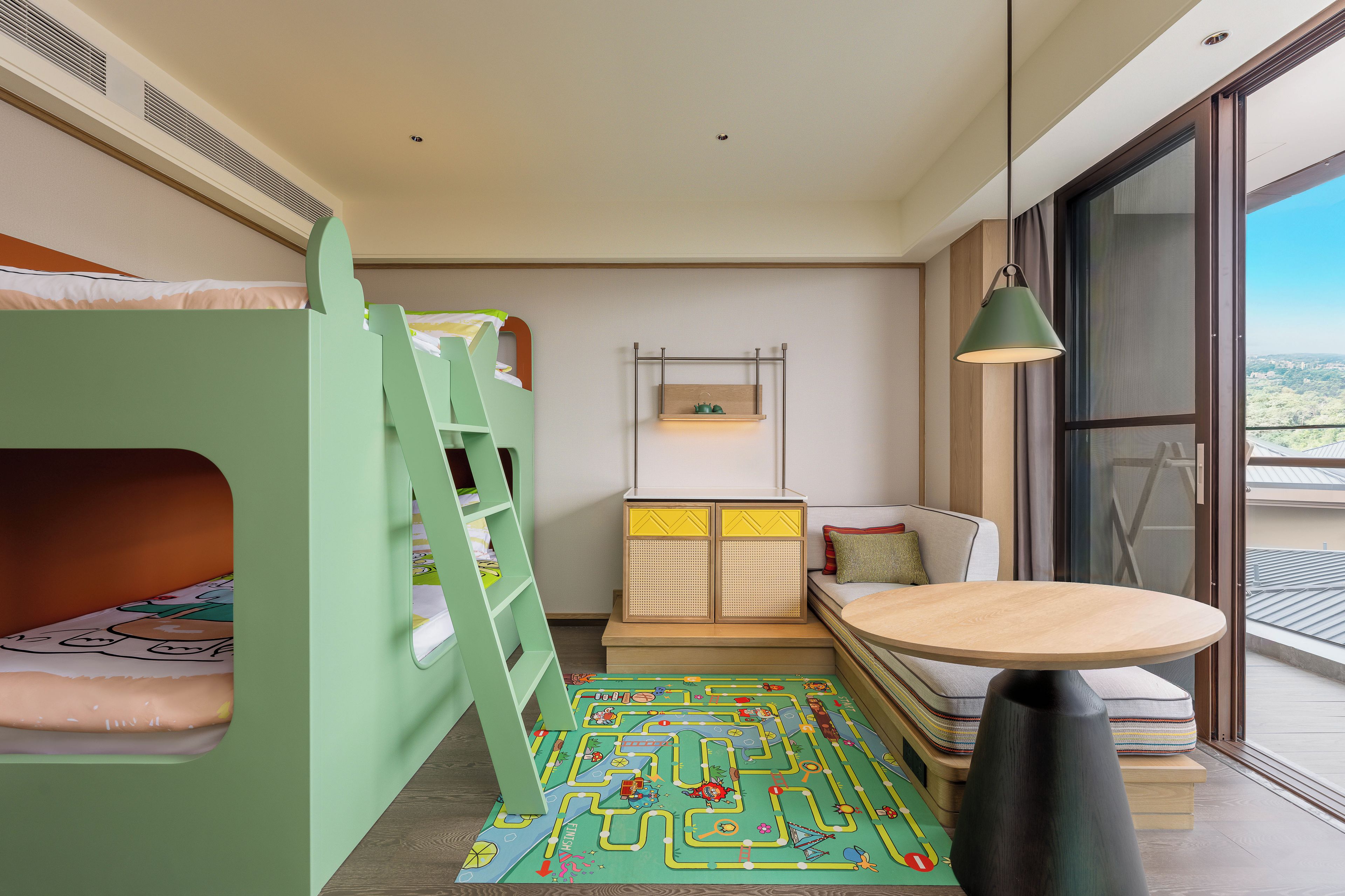 Zona de juegos infantil con literas, un tapete de juego y una pequeña mesa.