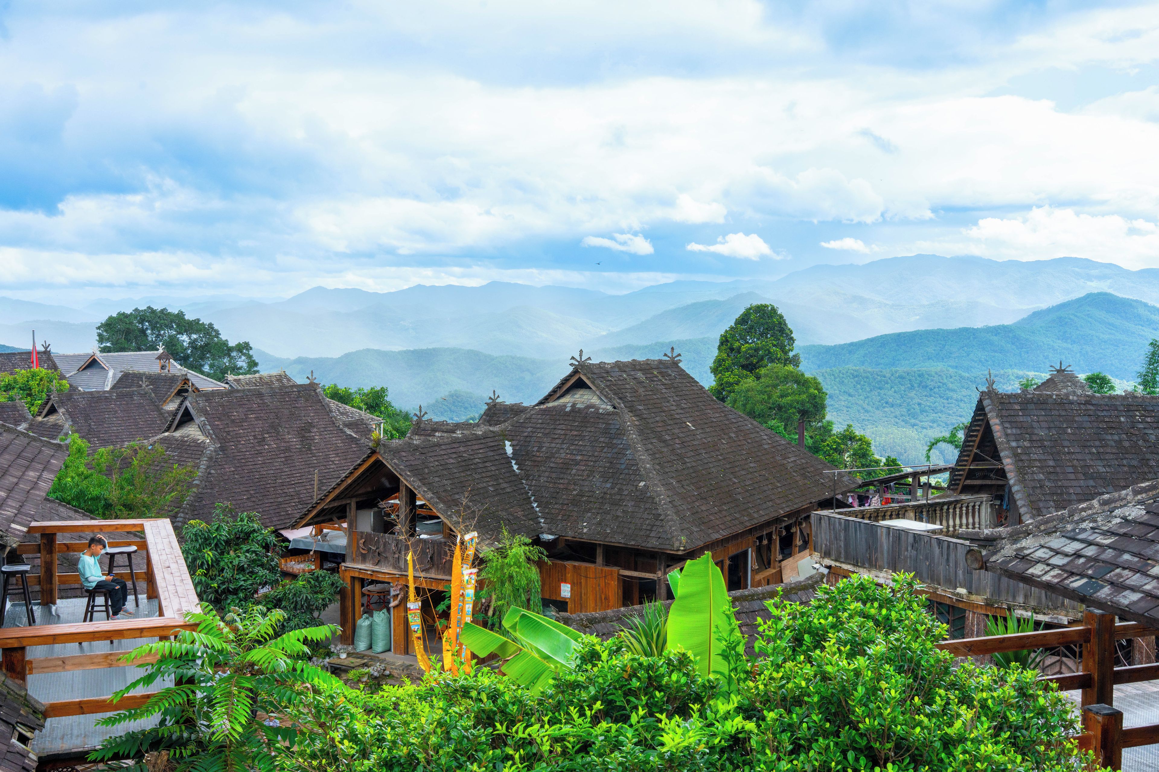 A traditional village with wooden houses and a mountainous backdrop.