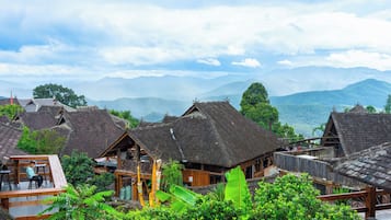 A traditional village with wooden houses and a mountainous backdrop.
