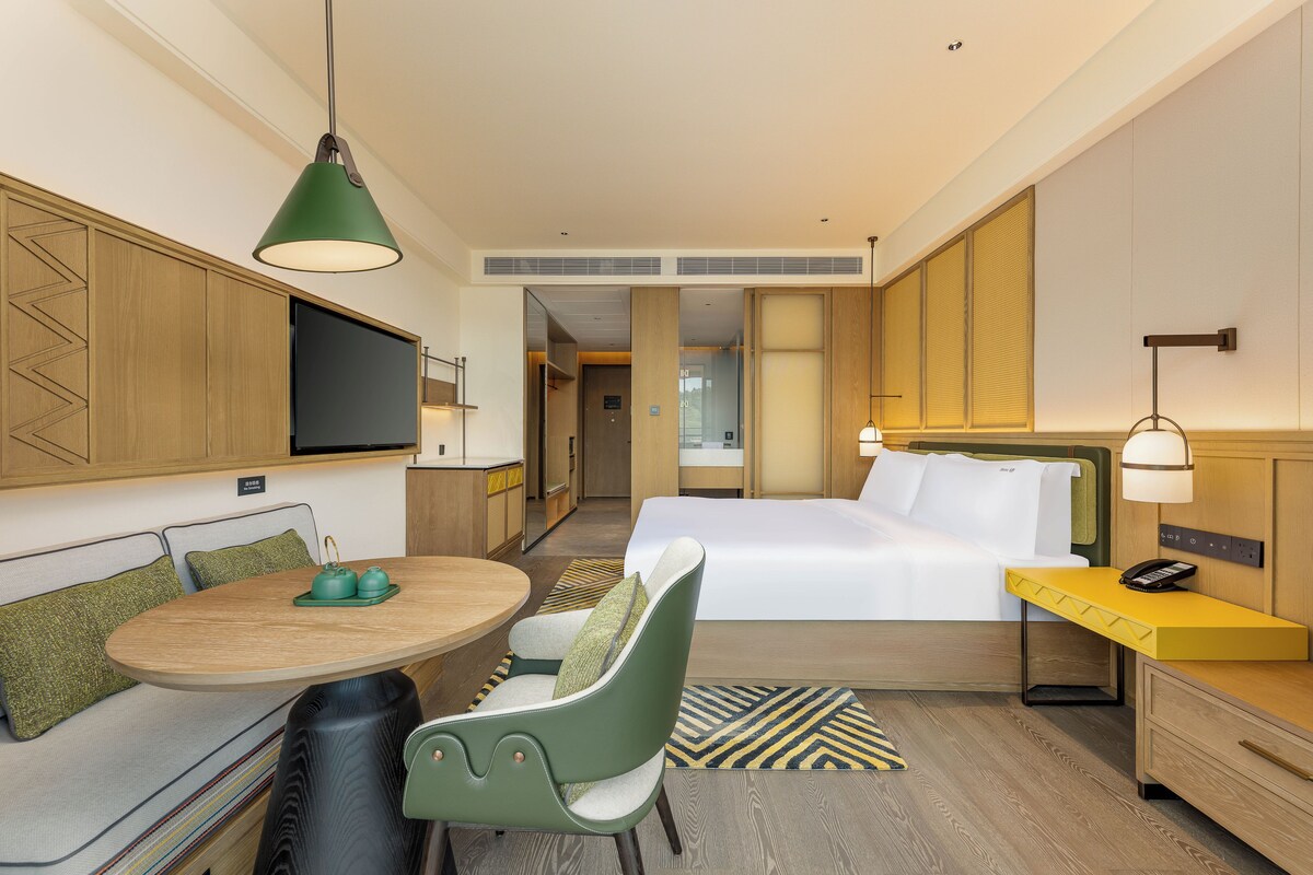 Una habitación de hotel con una cama, un escritorio, una silla, un televisor y un rincón de comedor.