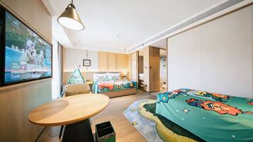 A hotel room with a bed, a small table, a TV, and a wall-mounted shelf.