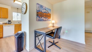 Una cocina moderna con armarios de madera, lavavajillas y un comedor con mesa y silla.