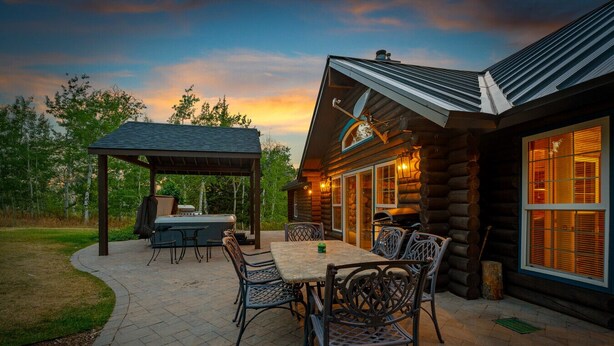 Une cabane en rondins dotée d’un patio couvert, de meubles d’extérieur et d’un barbecue.