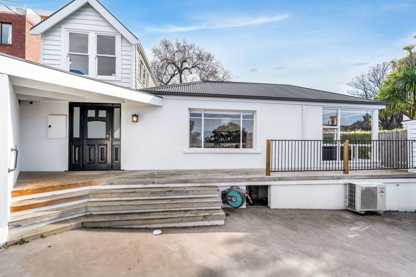 A modern two-story house with a front porch, a garage, and a small deck.