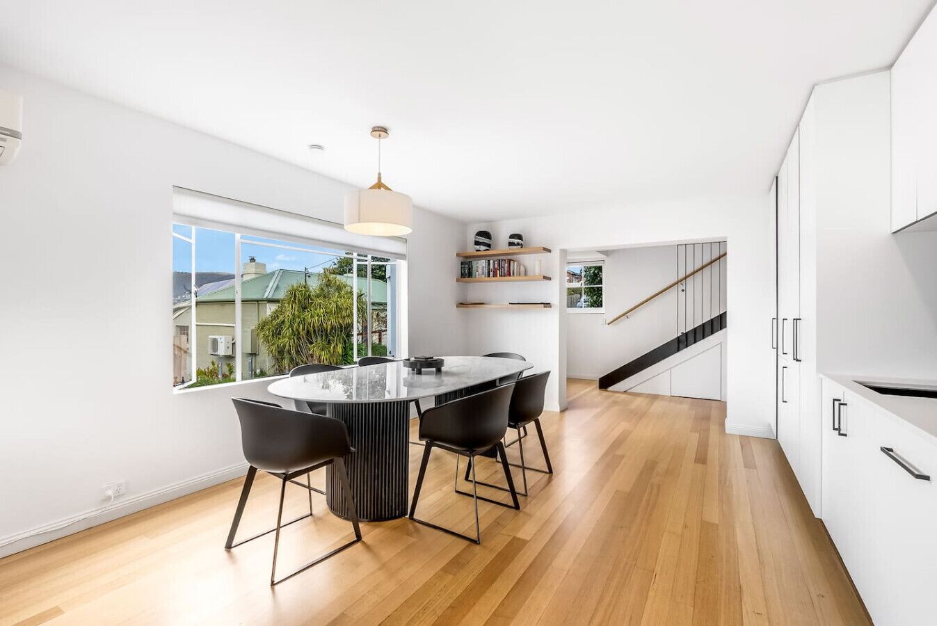 Una cocina moderna con una isla central, armarios blancos y vistas amplias por un gran ventanal.