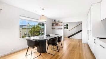 Una cocina moderna con una isla central, armarios blancos y vistas amplias por un gran ventanal.