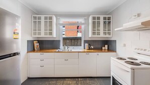 Una cocina moderna con armarios blancos, encimera de madera, estufa integrada y ventana con vista a un edificio de ladrillo.