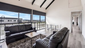 A spacious living area with a large window, a sofa, a coffee table, and a dining table with chairs. - Expansive River-View Oasis (Claremont)