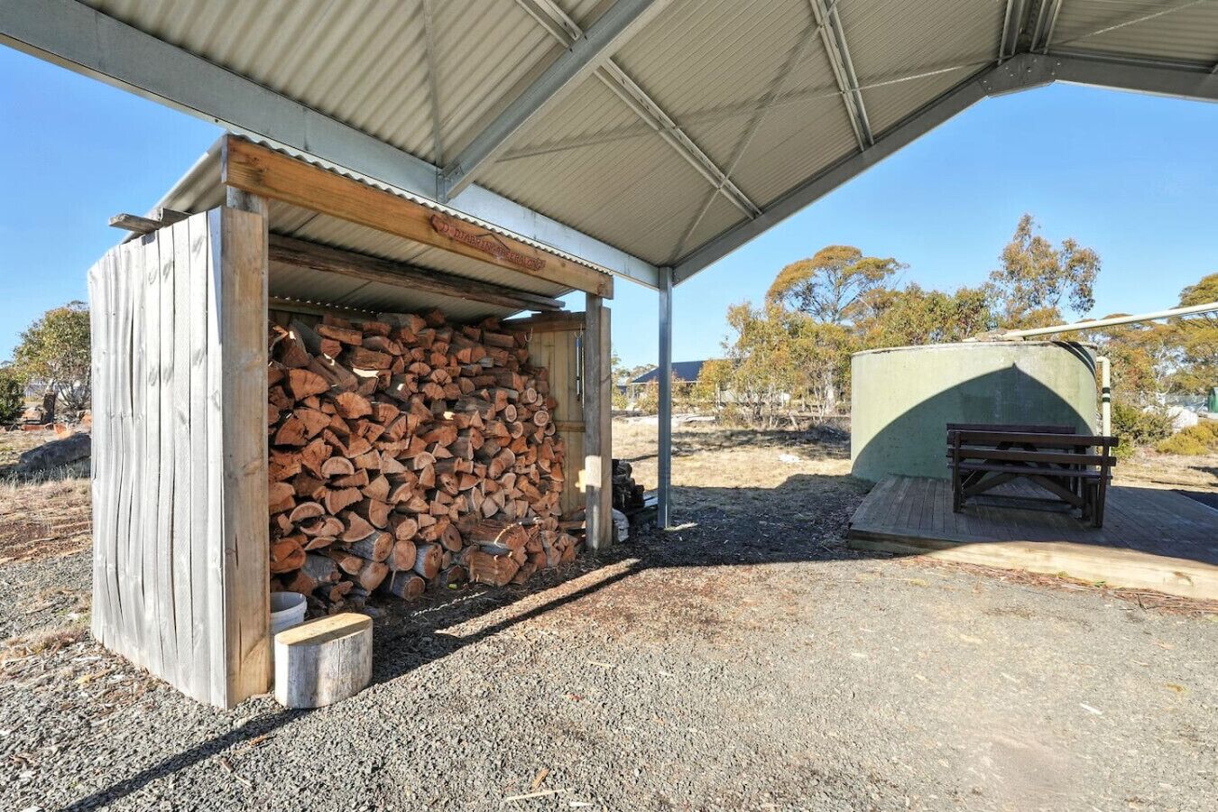 Un espacio al aire libre cubierto con una pila de leña y una pequeña construcción de madera.