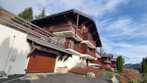 A multi-story wooden chalet with balconies, a garage, and a driveway leading to the entrance. - 7 minutes from the center and superb mountain views (Megève)