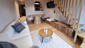 A modern living room with a wooden ceiling, a round coffee table, a sofa, and a built-in bench with a fur throw. - 7 minutes from the center and superb mountain views (Megève)