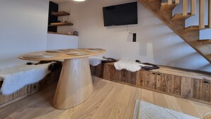 A modern interior with a wooden dining table, a mounted TV, and a wooden staircase. - 7 minutes from the center and superb mountain views (Megève)