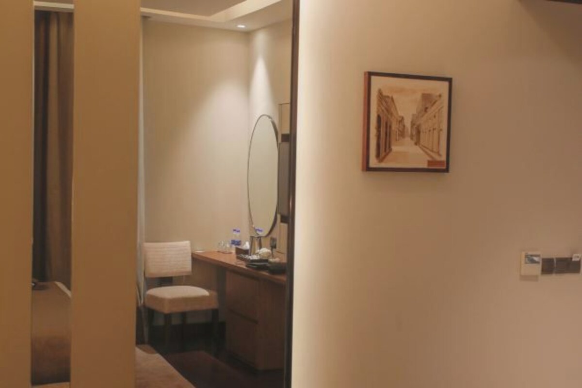 A hotel room with a desk, chair, and a large mirror.