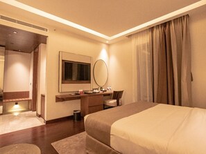 Ein Hotelzimmer mit Bett, Schreibtisch, Stuhl, Spiegel und einem Fenster mit Vorhängen.