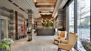 A modern lobby with marble flooring, a reception desk, and seating areas.