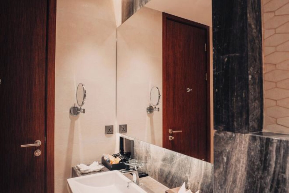 A modern bathroom with a large mirror, a sink, and a marble countertop.